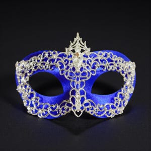 May include: A vibrant blue masquerade mask with intricate silver filigree. The mask has a central jewel and ornate silver detailing around the eye openings, offering an elegant and decorative design for special events.