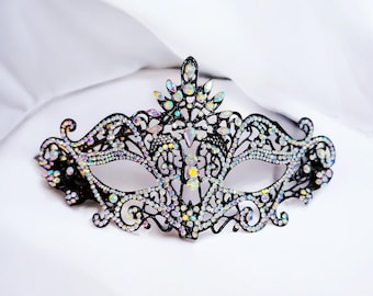 May include: A black masquerade mask with intricate lace detailing and iridescent rhinestones.
