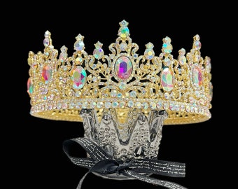 May include: A gold crown with iridescent rhinestones and a black ribbon. The crown is on a black stand with the words "Happy Jewelry World" printed on it.