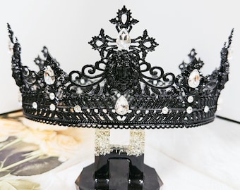 May include: A black crown with clear, sparkling gemstones. The crown is ornate with a filigree design and is displayed on a black stand with the text "YOU DESERVE THE BEST". The crown is likely for a special occasion.