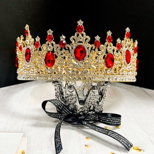 Op de afbeelding: Een gouden kroon met rode juwelen en een zilveren basis. De kroon is versierd met ingewikkelde details en is een prachtig sieraad.