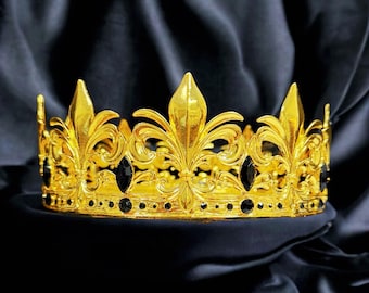 以下が含まれることがあります： 黒い宝石がついた金の王冠。王冠は百合の花の模様で、黒い背景に置かれています。