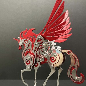 May include: A red and silver metal sculpture of a winged horse with intricate details. The horse has a flowing mane and tail, and its wings are spread wide. The sculpture is mounted on a silver base.