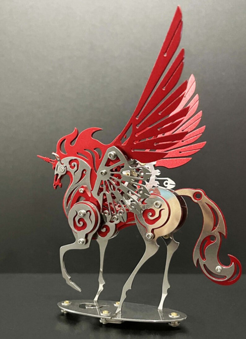 May include: A red and silver metal sculpture of a winged horse with intricate details. The horse has a flowing mane and tail, and its wings are spread wide. The sculpture is mounted on a silver base.