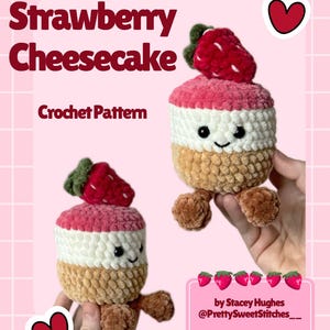 May include: Two plush crochet strawberry cheesecake toys with smiling faces. The toys have a strawberry on top, pink and white layers, and a tan base. The image includes the text "Strawberry Cheesecake Crochet Pattern".