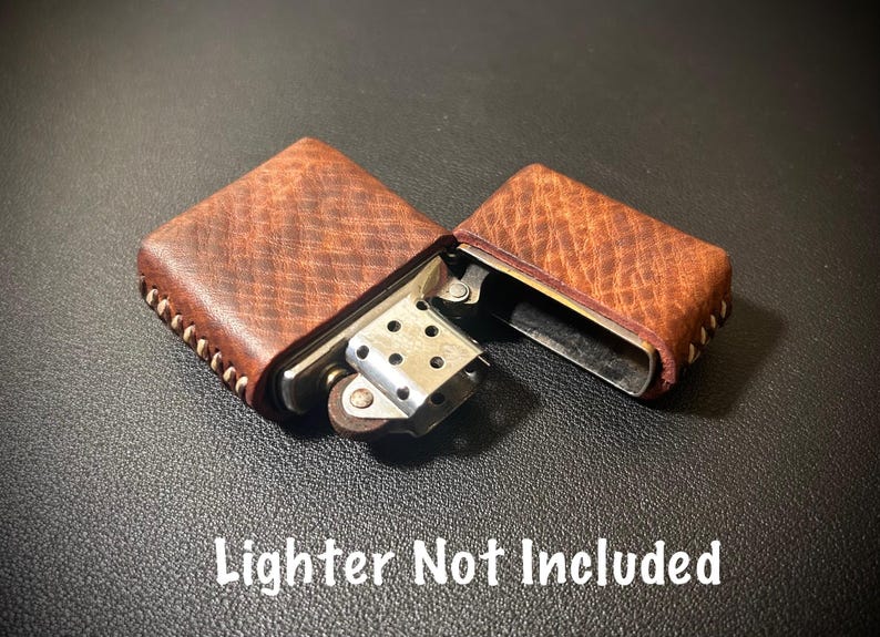 May include: A brown leather lighter case with white stitching. The case is open and the lighter is not included. "Lighter Not Included" is written in white text on a black background.