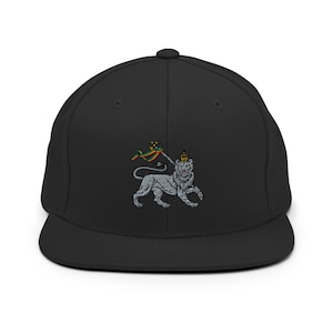 Pode incluir: Boné de beisebol preto ajustado com um leão bordado usando uma coroa e segurando uma bandeira com cores vermelha, amarela e verde.