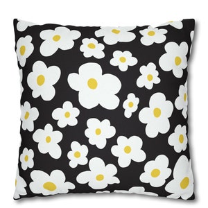 May include: A black throw pillow with a white daisy pattern. The daisies have yellow centers.