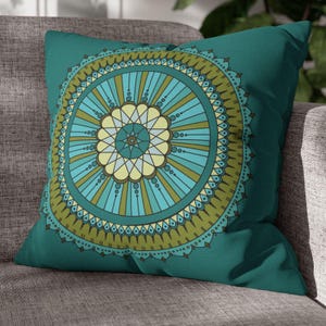 May include: Teal blue throw pillow with a green and blue mandala design.