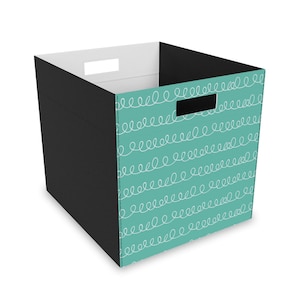 May include: A teal storage bin with a black lid and white doodle pattern. The bin has a cutout handle on the top.