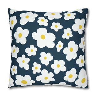May include: A navy blue throw pillow with a white and yellow daisy pattern.