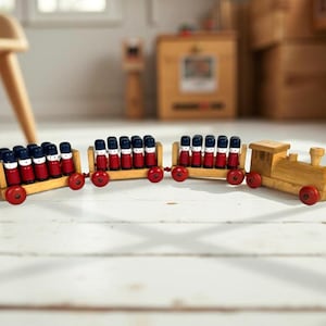 May include: A wooden toy train with three cars and a locomotive. The train cars are filled with small, red and blue figures. The train has red wheels and is made of light-colored wood.