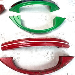 May include: Four vintage cabinet door handles. Two are red with white stripes, one is green with a chrome trim, and one is green.