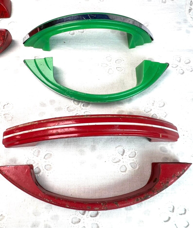 May include: Four vintage cabinet door handles. Two are red with white stripes, one is green with a chrome trim, and one is green.