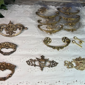 May include: Assortment of antique brass drawer pulls and handles. Some are ornate with floral designs, others are simple and elegant.  There are also two sets of screws included.