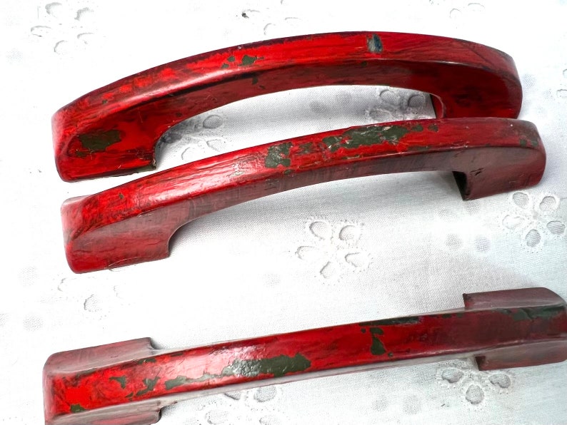 May include: Three red painted metal door handles with a distressed finish. The handles are in the shape of an arch.