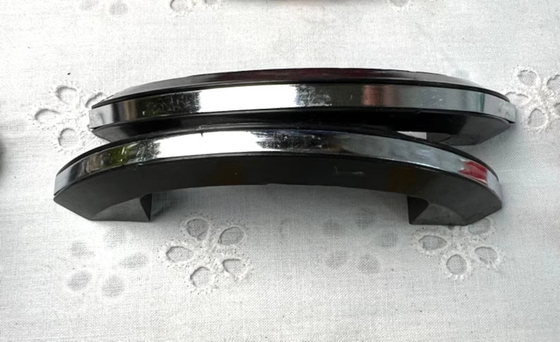 May include: Two black and chrome cabinet door handles. The handles are curved and have a polished chrome finish.