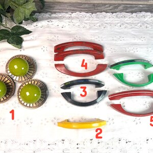 May include: Assortment of six vintage cabinet knobs in various colors, including red, green, blue, and yellow. The knobs are made of plastic and have a smooth, rounded shape. They are perfect for adding a touch of vintage charm to any home.