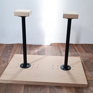 Könnte beinhalten: Zwei Holz-Handstände mit schwarzen Metallstangen, die auf einer Holzbasis montiert sind. Die Basis hat mehrere Löcher für die Montage.