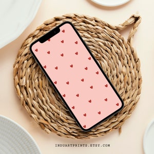 May include: A smartphone displays a pink background with a pattern of small red hearts. The phone rests on a round, woven placemat. The Etsy shop name, INDUARTPRINTS.ETSY.COM, is visible at the bottom.