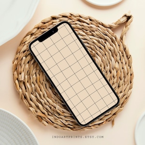 Puede incluir: Un teléfono inteligente negro con un patrón de cuadrícula en la pantalla está sobre una estera de paja tejida.