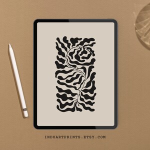 May include: Black and white abstract art print featuring a stylized plant with wavy lines. The print is displayed on a tablet screen with a brown background.