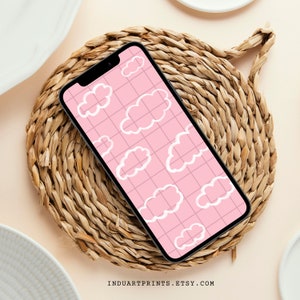 May include: A pink phone case with a white cloud pattern. The case is on a woven straw coaster.