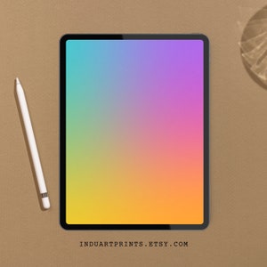 Puede incluir: Una tableta con un fondo degradado de arcoíris sobre una superficie marrón. Un lápiz blanco está a la izquierda de la tableta.