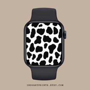 Könnte beinhalten: Eine schwarze Smartwatch mit einem weißen und schwarzen Kuhflecken-Zifferblatt.