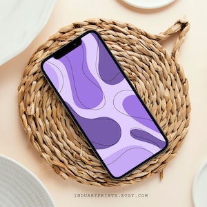 May include: A purple and white abstract phone wallpaper with a wavy, organic design. The phone is on a woven straw coaster.