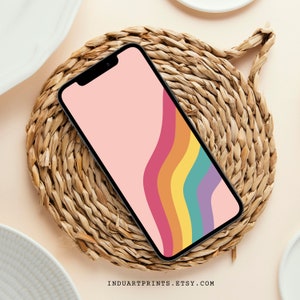 Può includere: Uno smartphone che mostra una carta da parati astratta colorata con linee ondulate in tonalità di rosa, arancio, giallo, verde e viola. Il telefono è appoggiato su un tappetino di paglia intrecciato.