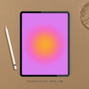 May include: A digital tablet displays a vibrant gradient of pink, purple, and yellow hues. A white stylus rests beside the tablet on a textured brown surface. The text "INDUARTPRINTS.ETSY.COM" is visible at the bottom of the screen.