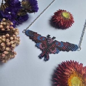 May include: A beaded butterfly necklace with a silver chain. The butterfly is made of red, blue, black, and brown beads.