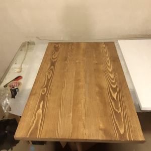 K&ouml;nnte beinhalten: Eine rechteckige Tischplatte aus Holz mit hellbraunem Finish. Die Holzmaserung ist sichtbar und verl&auml;uft in L&auml;ngsrichtung &uuml;ber die Oberfl&auml;che. Die Tischplatte ist etwa 152 cm lang und 76 cm breit.
