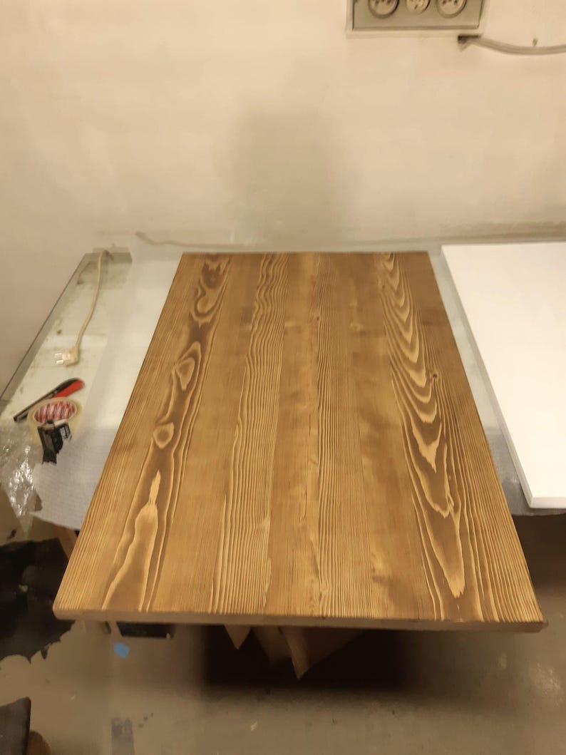 K&ouml;nnte beinhalten: Eine rechteckige Tischplatte aus Holz mit hellbraunem Finish. Die Holzmaserung ist sichtbar und verl&auml;uft in L&auml;ngsrichtung &uuml;ber die Oberfl&auml;che. Die Tischplatte ist etwa 152 cm lang und 76 cm breit.