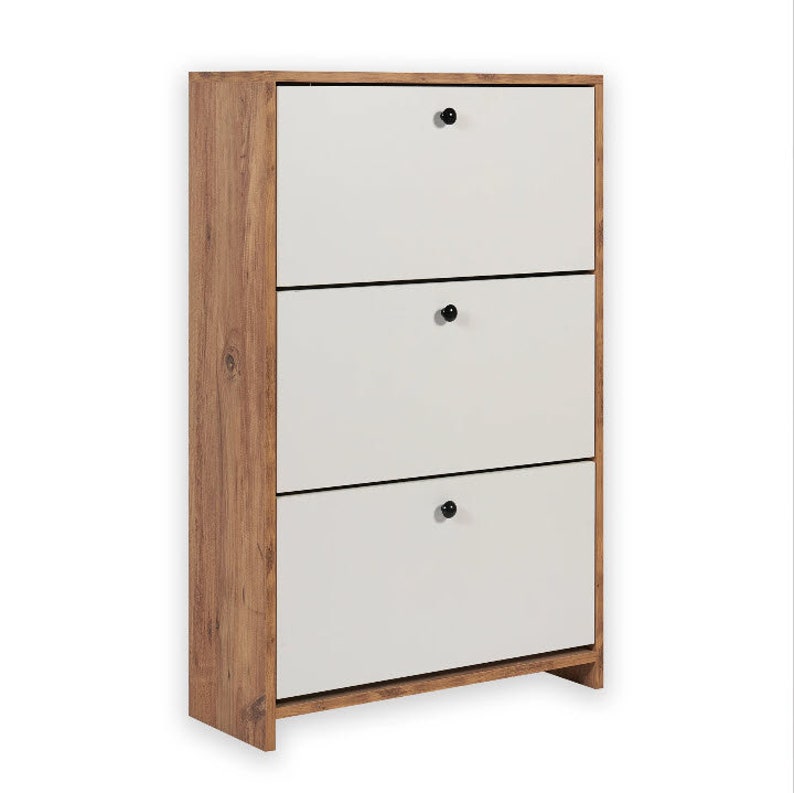 May include: A three-tier shoe cabinet with a light wood finish and white doors. Each door has a black knob.