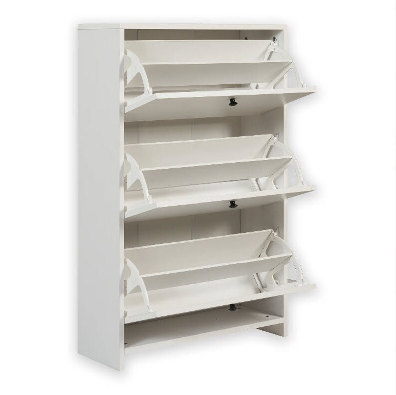 May include: White shoe storage cabinet with three shelves that have flip-down doors. Each shelf has a white, angled, flip-down door.