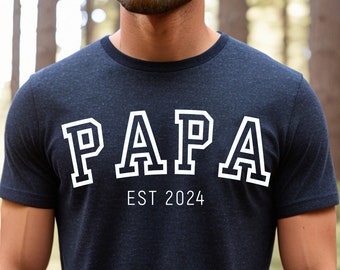 May include: A navy blue t-shirt with white text that reads "PAPA EST 2024".