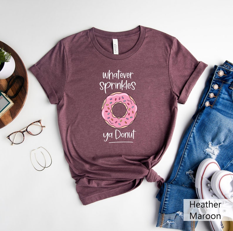 May include: A heather maroon t-shirt with a pink donut graphic and the text "Whatever sprinkles ya donut".