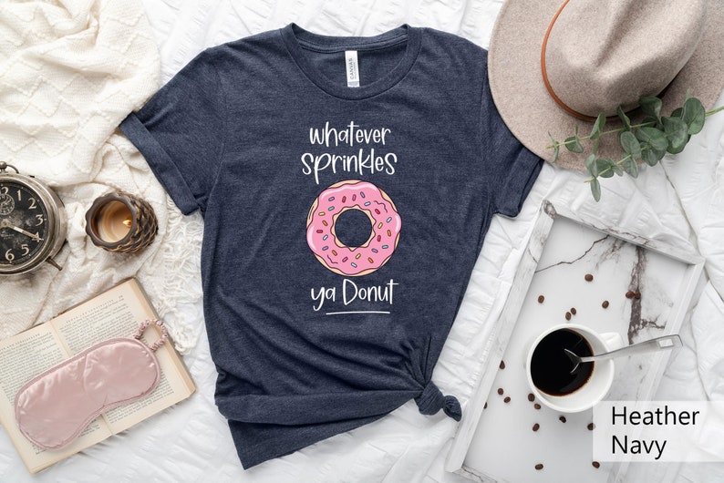 May include: A heather navy blue t-shirt with a pink donut graphic and the text "whatever sprinkles ya donut".