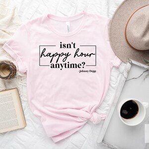 May include: Pink t-shirt with the text "isn't happy hour anytime? -Johnny Depp" printed on it.