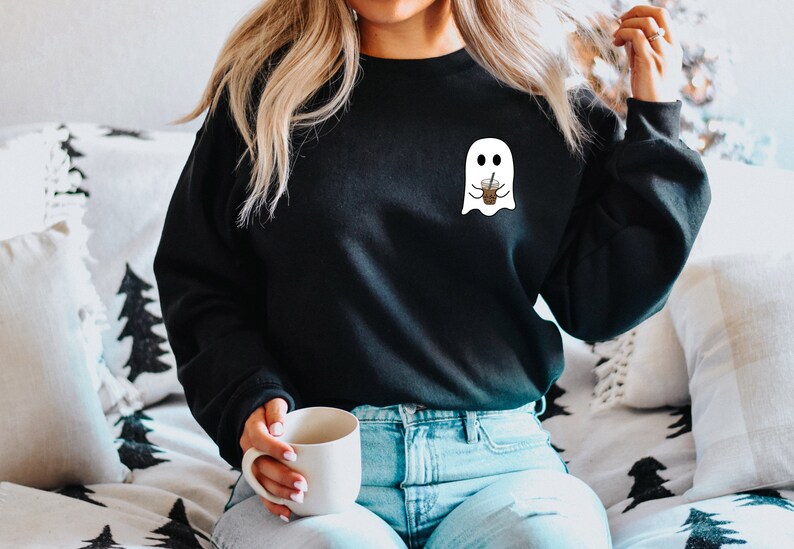Puede incluir: Sudadera negra con un gr&aacute;fico de fantasma blanco sosteniendo una taza de caf&eacute;. El fantasma tiene una expresi&oacute;n amigable. La sudadera es de estilo casual, adecuada para el uso diario. El dise&ntilde;o es simple y juguet&oacute;n, perfecto para Halloween o los amantes del caf&eacute;.