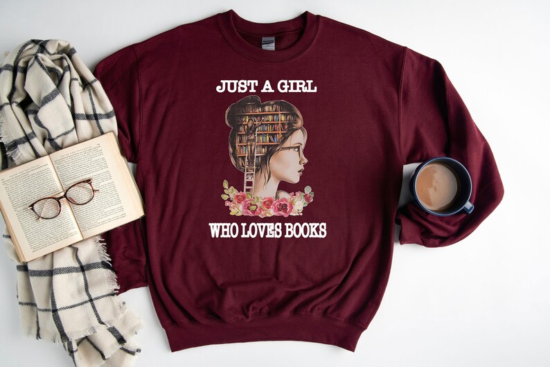 Pu&ograve; includere: Felpa color borgogna con una grafica di una donna con una libreria per la testa e il testo "Just a girl who loves books".
