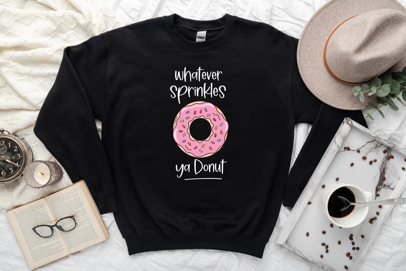 May include: Black sweatshirt with a pink and white donut graphic and the text "whatever sprinkles ya donut".