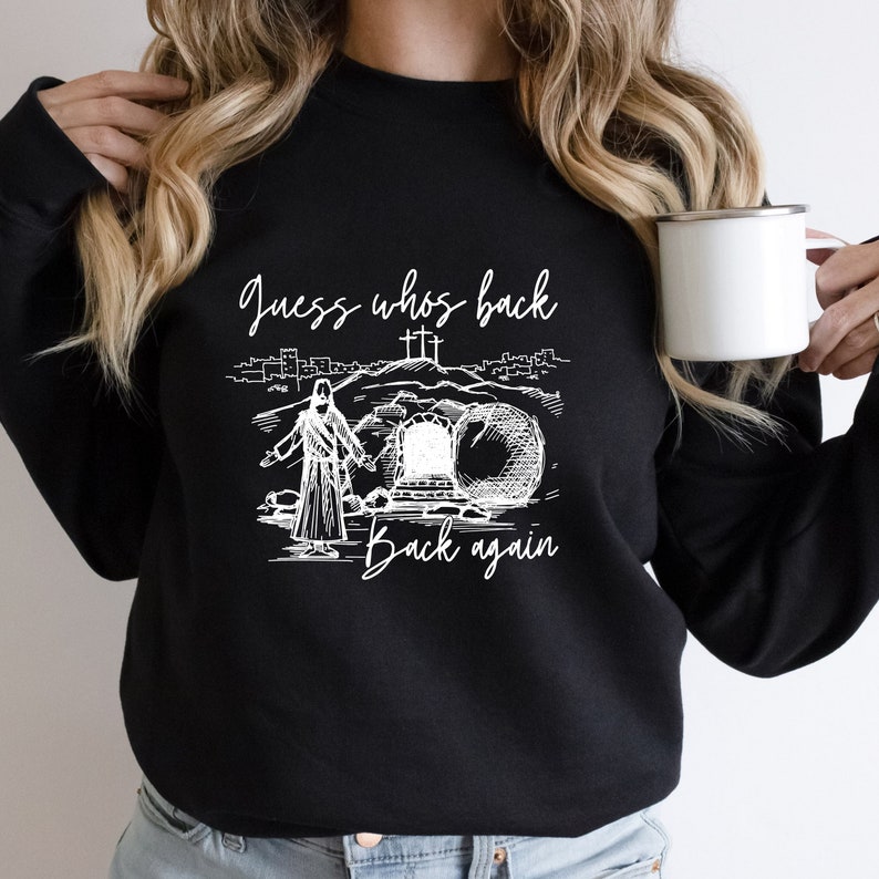 May include: Black sweatshirt with a white graphic of Jesus walking away from a tomb with a large stone rolled away. The text "Guess who's back back again" is printed on the sweatshirt.