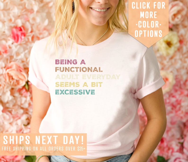 May include: A pink t-shirt with the text "BEING A FUNCTIONAL ADULT EVERYDAY SEEMS A BIT EXCESSIVE" in a rainbow gradient. The text is centered on the shirt. The shirt is being worn by a person. The text "SHIPS NEXT DAY! FREE SHIPPING ON ALL ORDERS OVER $35+" is at the bottom of the image. The text "CLICK FOR MORE -COLOR- OPTIONS" is in the top right corner of the image.
