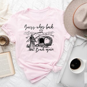 May include: Pink t-shirt with a black and white illustration of Jesus walking out of a tomb with the text "Guess who's back back again".