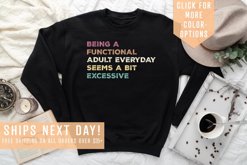 May include: Black sweatshirt with the text "BEING A FUNCTIONAL ADULT EVERYDAY SEEMS A BIT EXCESSIVE" in colorful retro lettering.