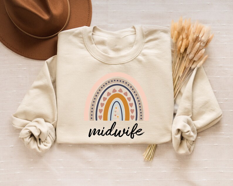 Peut inclure: Un sweat-shirt beige avec un motif arc-en-ciel et le mot "sage-femme" imprim&eacute; dessus.