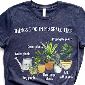 以下が含まれることがあります： 「THINGS I DO IN MY SPARE TIME」というテキストと、植物に関連する活動のリスト（「Propagate plants」、「Repot plants」、「Water plants」、「Buy plants」、「Rearrange plants」、「Talk with plants」など）が書かれたネイビーブルーのTシャツ。テキストは白で、画像には鉢植えの植物のイラストが含まれています。